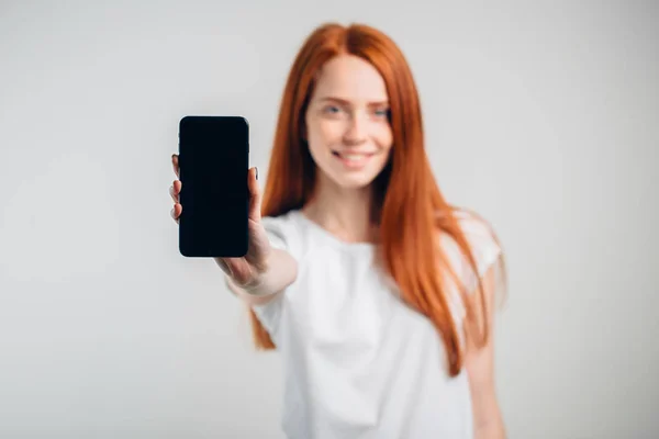 Счастливая женщина показывает чистый экран смартфона. Сосредоточьтесь на смартфоне . — стоковое фото