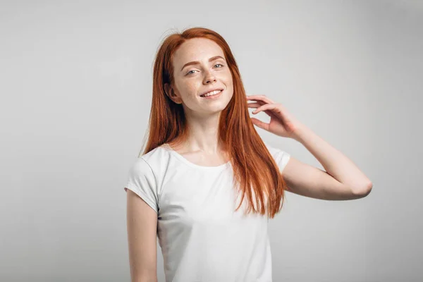 Mädchen lächelt mit geschlossenen Augen und berührt ihr rotes Haar vor weißem Hintergrund — Stockfoto