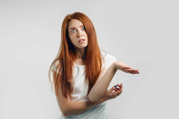 Förbryllad och aningslös ung rödhårig kvinna med armar ut — Stockfoto