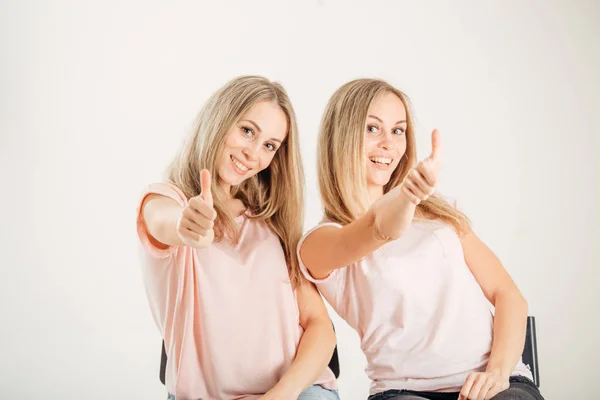 Tweelingzusjes met duimen omhoog op wit — Stockfoto