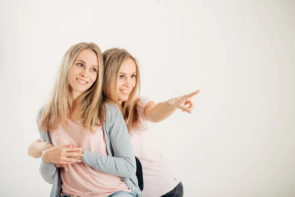 Dos hermanas gemelas atractivas señalando sobre fondo blanco — Foto de Stock
