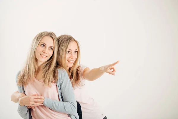 Duas irmãs atraentes gêmeos apontando sobre fundo branco — Fotografia de Stock