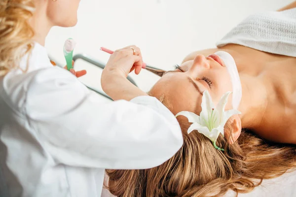 Femeie obtinerea de îngrijire facială de cosmetician la salon spa, vedere laterală, close-up . — Fotografie, imagine de stoc