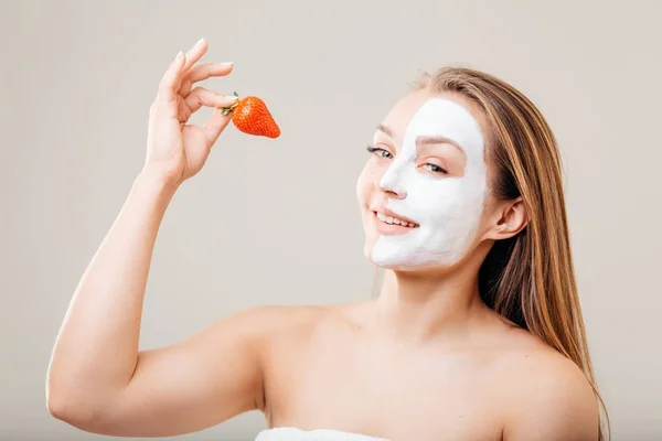 Wanita muda cantik dengan masker wajah dan strawberry, perawatan spa — Stok Foto