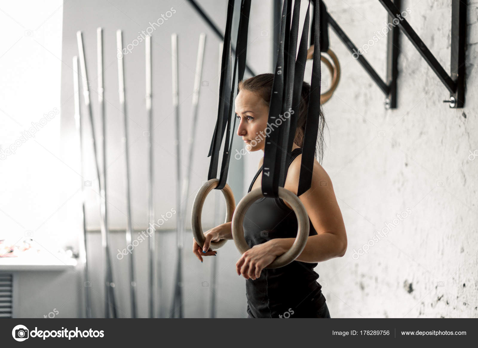 Determined woman exercising with gymnastic rings in gym stock