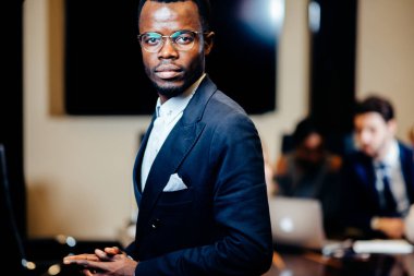 Afrika işadamı kamerada grup arka plan üzerinde iş adamları ile seyir