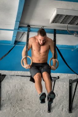 Jimnastik halkaları üzerinde spor salonunda yoğun egzersiz yapan kas-up egzersiz atletik erkek