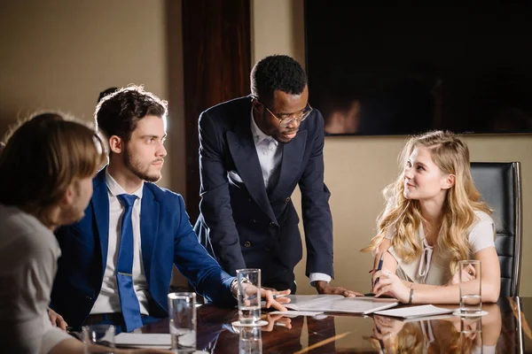 female team leader talking with mixed race group of people in office