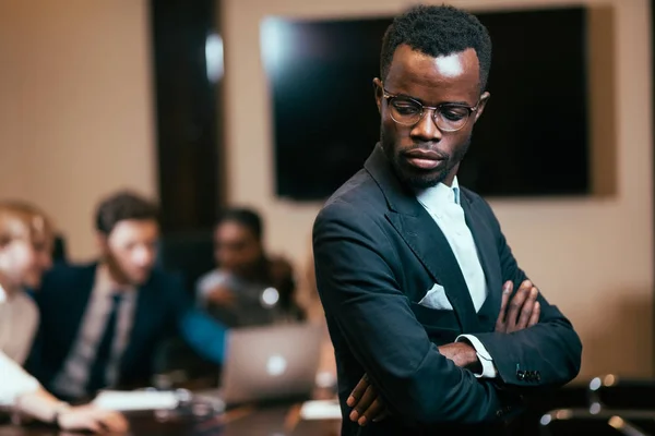 Africano uomo d'affari guardando sulla macchina fotografica con gruppo di uomini d'affari su sfondo — Foto Stock