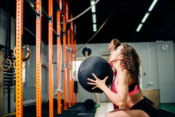 Dos mujeres lanzan bolas de medicina en el gimnasio de fitness — Foto de Stock