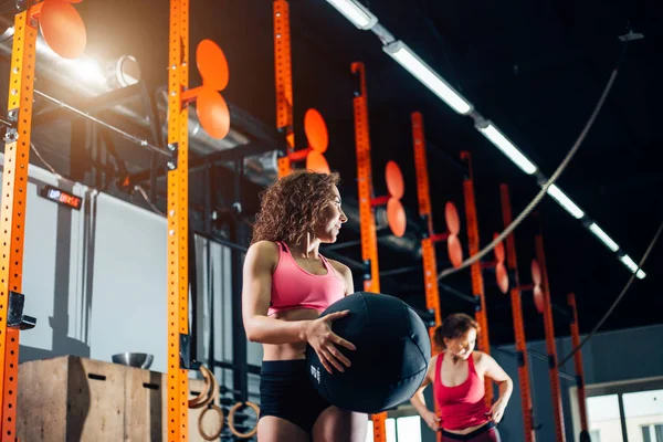 Fitness- und Trainingskonzept - zwei Frauen mit Medizinbällen trainieren im Fitnessstudio — Stockfoto