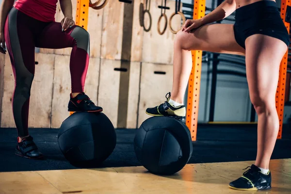 Foto de la cosecha de dos mujeres poner los pies en las bolas de medicina en el gimnasio — Foto de Stock