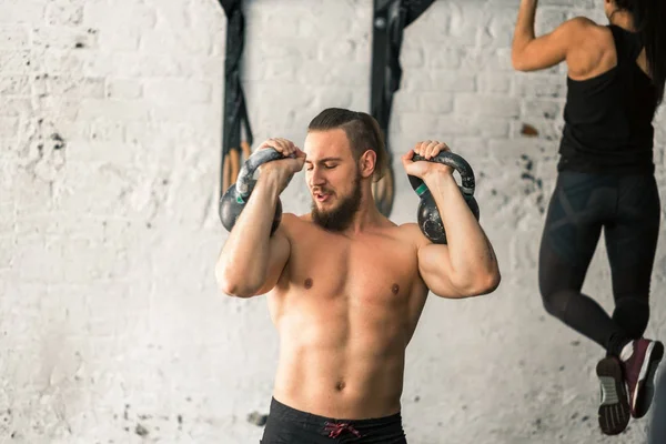 Homem levantando dois kettlebell exercício no ginásio — Fotografia de Stock