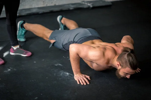 Zijaanzicht van de jonge knappe man in sportkleding doen push-up op sportschool — Stockfoto