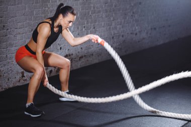 Savaş halatları seansı. Çekici genç fit ve formda sporcu kadın antrenmanı.