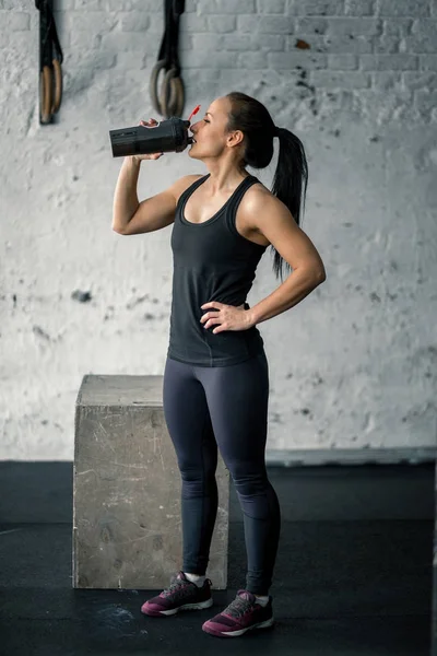 Menina beber água no ginásio após o treino — Fotografia de Stock
