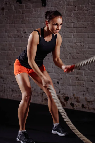 Atletisk kvinna gör vissa cross fit övningar med slaget rep inomhus — Stockfoto