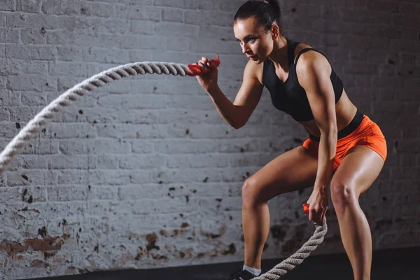 Entrenamiento de mujer con cuerda de batalla en gimnasio cross fit —  Fotos de Stock