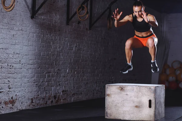 Mujer en forma haciendo ejercicio de salto de caja. Musculosa mujer haciendo saltos de caja en el gimnasio — Foto de Stock