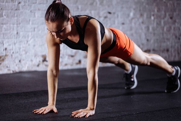 beautiful woman in sportswear doing plank while trainnig at cross fit gym