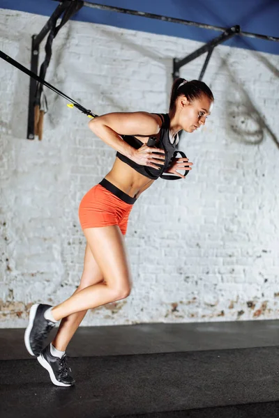 Trx concept. lady exercising her muscles with help of suspension trainer sling