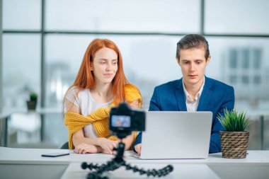 İki video blogcusu bir şey hakkında konuşuyor ve gülümsüyor.
