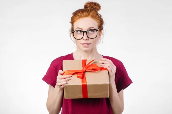 Mujer pelirroja feliz en gafas sosteniendo caja de regalo sobre fondo blanco —  Fotos de Stock