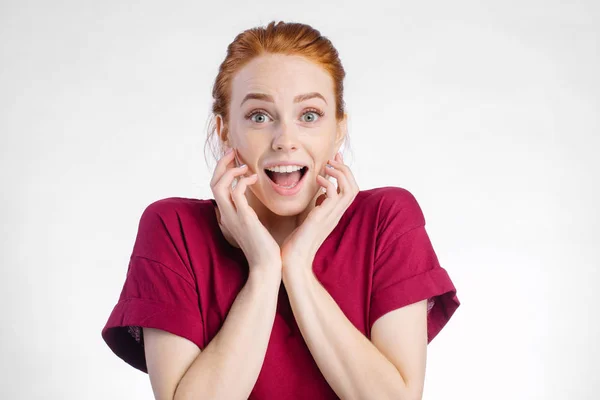 Surprised redhead woman in red shirt over white background — Stock Photo, Image