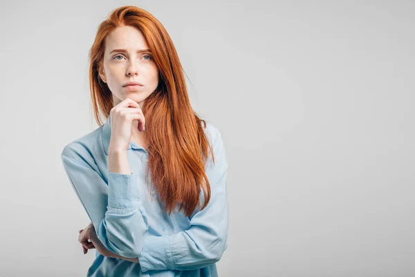 Redhead young Caucasian woman holding arm on her chin and looking up sideways — Stock Photo, Image
