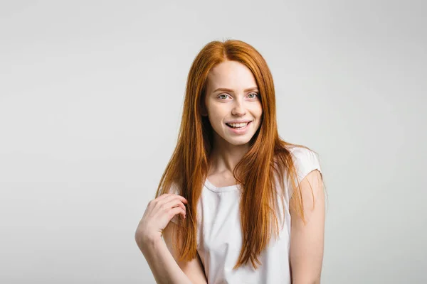 Menina sorrindo com os olhos fechados tocando seu cabelo vermelho sobre fundo branco — Fotografia de Stock