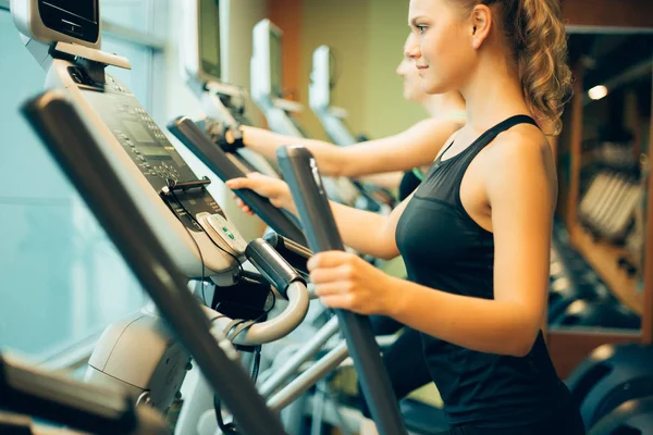 Mujer haciendo ejercicio en máquinas de cross trainer . — Foto de Stock