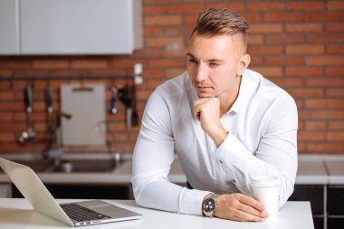 adam evde laptop arıyorum beyaz masada oturan bir proje üzerinde