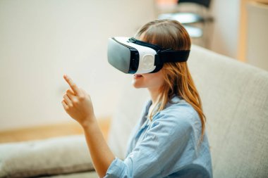 onun Vr kulaklık ayarlama ve halı üzerinde evde otururken gülümseyen kadın