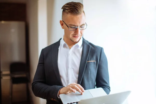 Hombre guapo con gafas de trabajo con el ordenador portátil en la oficina — Foto de Stock