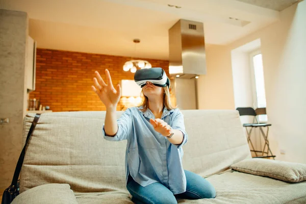 Mujer ajustando sus auriculares VR y sonriendo mientras está sentada en la alfombra en casa — Foto de Stock