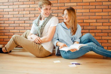 Genç çift evde ahşap katta oturan bir kitap okuma