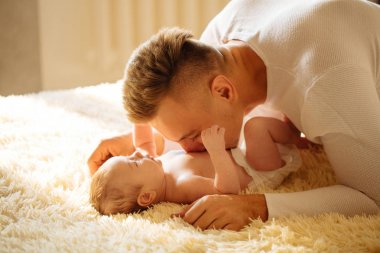 Yatakta yatarken babası ve onun bebeği tutar