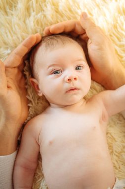 Kameraya bakıyor bebeğim, beyaz battaniye üzerinde yatıyordu