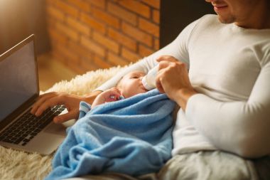 adam yatakta yatarken ve dizüstü bilgisayarda çalışma sırasında küçük bebek beslenme