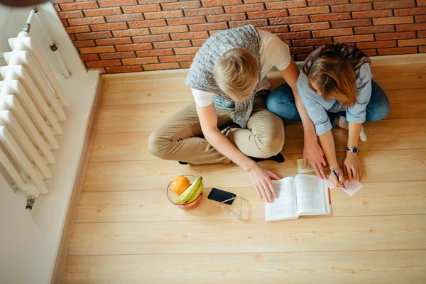 Fiatal pár ül a fa padló otthon olvasott — Stock Fotó