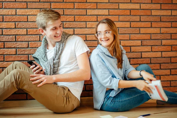 Mladý pár s knihou sedět na dřevěné podlaze doma — Stock fotografie