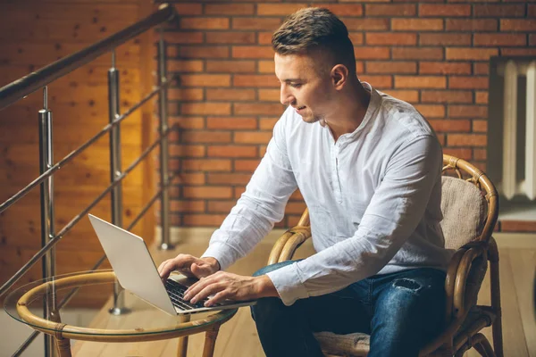 Człowiek siedzi w domu i pracy na laptopie. mężczyzna pracy z domowego biura loft — Zdjęcie stockowe