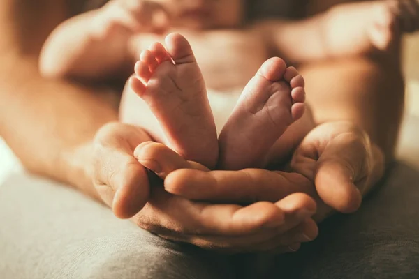 Mother holds newborn babys feets. Tiny feet in womans hand. — Stock Photo, Image
