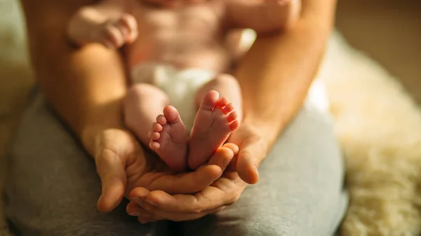 Bebe ayak anne elinde. Yeni doğan bebek ayakları eller üzerinde — Stok fotoğraf