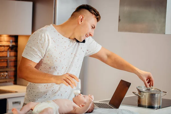 Pai solteiro trabalhando no computador portátil em casa enquanto cuida de seu filho bebê — Fotografia de Stock