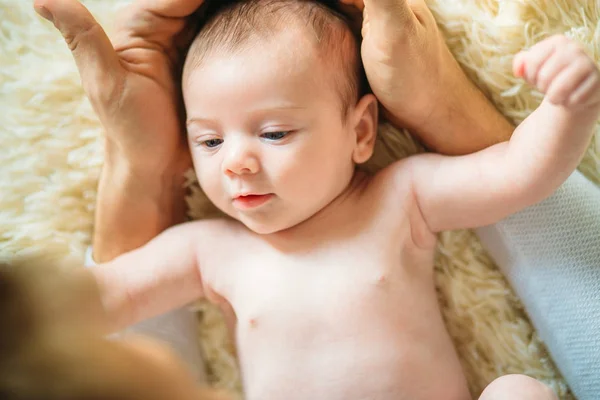 生まれたばかりの赤ちゃんが父親の頭を押しながらカメラを見て笑みを浮かべて横たわって — ストック写真
