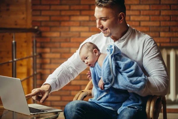 Батько з новонародженою дитиною працює з дому використовуючи ноутбук — стокове фото