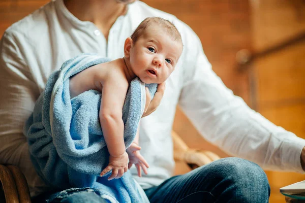 Człowiek pracy przy biurku w domu z laptopem, trzymając Ładna babys, patrząc na ekran — Zdjęcie stockowe