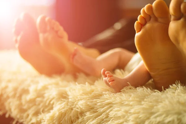 Familia acostada en la cama, sus pies en foco. Madre, padre e hijo recién nacido —  Fotos de Stock