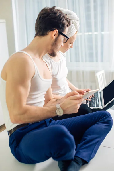男子手持平板电脑刺探他的女友笔记本电脑, 而她正在键入消息 — 图库照片
